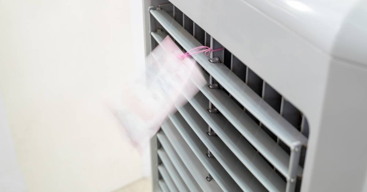 A closeup of an evaporative cooler with a pink tag attached to one of its vents blowing as it moves air.